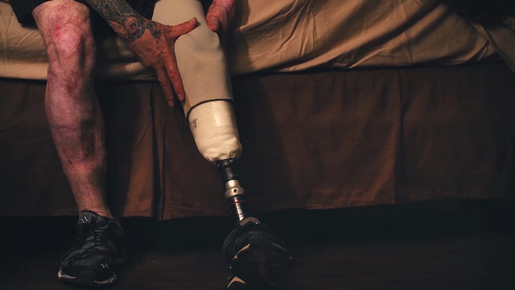 Veterans and Sacrifice shown through video production by scenic road, showing a man attaching his prostethic leg, required after combat. 