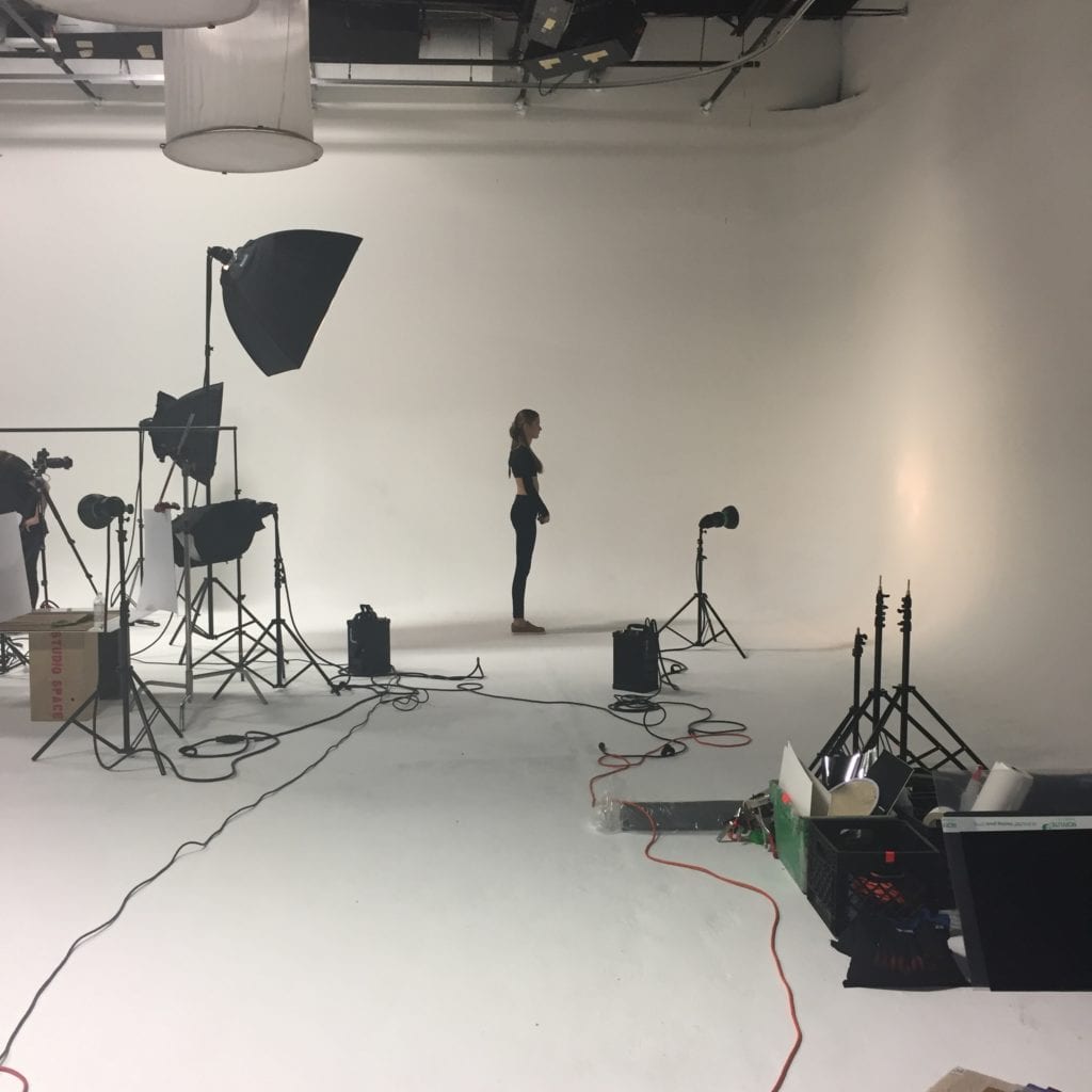Model for video production standing in a white cyclorama studio
