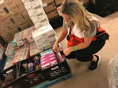 volunteer kneels by box for disaster relief