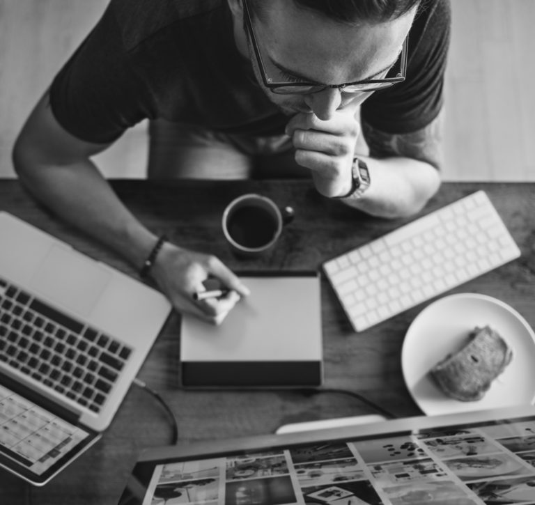 man sitting at desk with computer and coffee shot from above