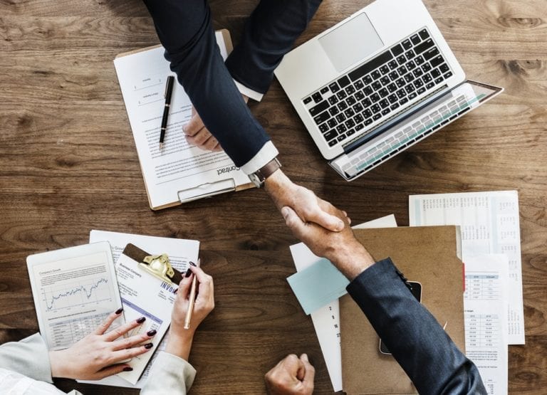 Overhead view of two people shaking hands over a table