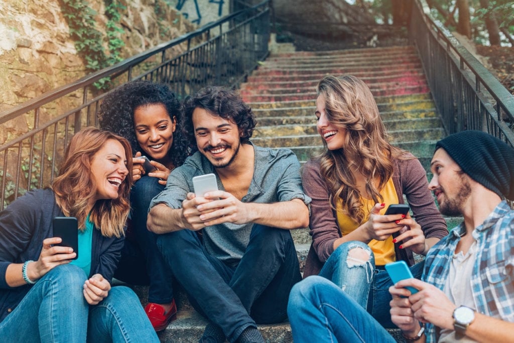 Multi-ethnic group of friends with smart phones sitting on a staircase