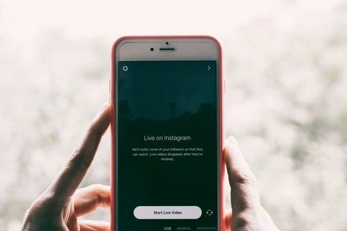 person's hands holding an iphone displaying a live on instagram notification screen
