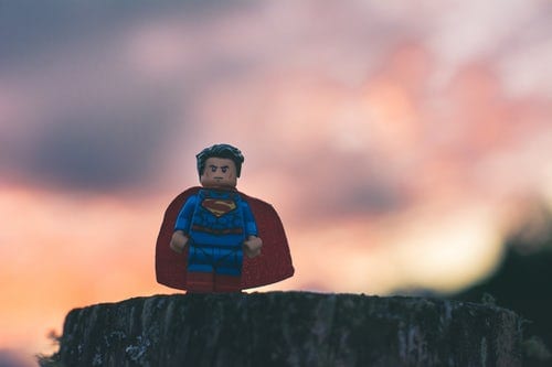 tiny lego superman figure standing on a tree stump in front of a sunset showcasing a video storytelling example
