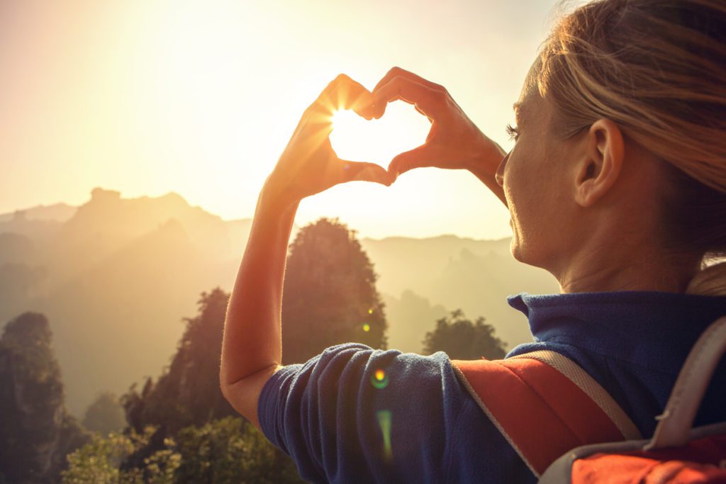 Young woman hiking in the Zhangjiajie National Forest park, makes a heart shape finger frame