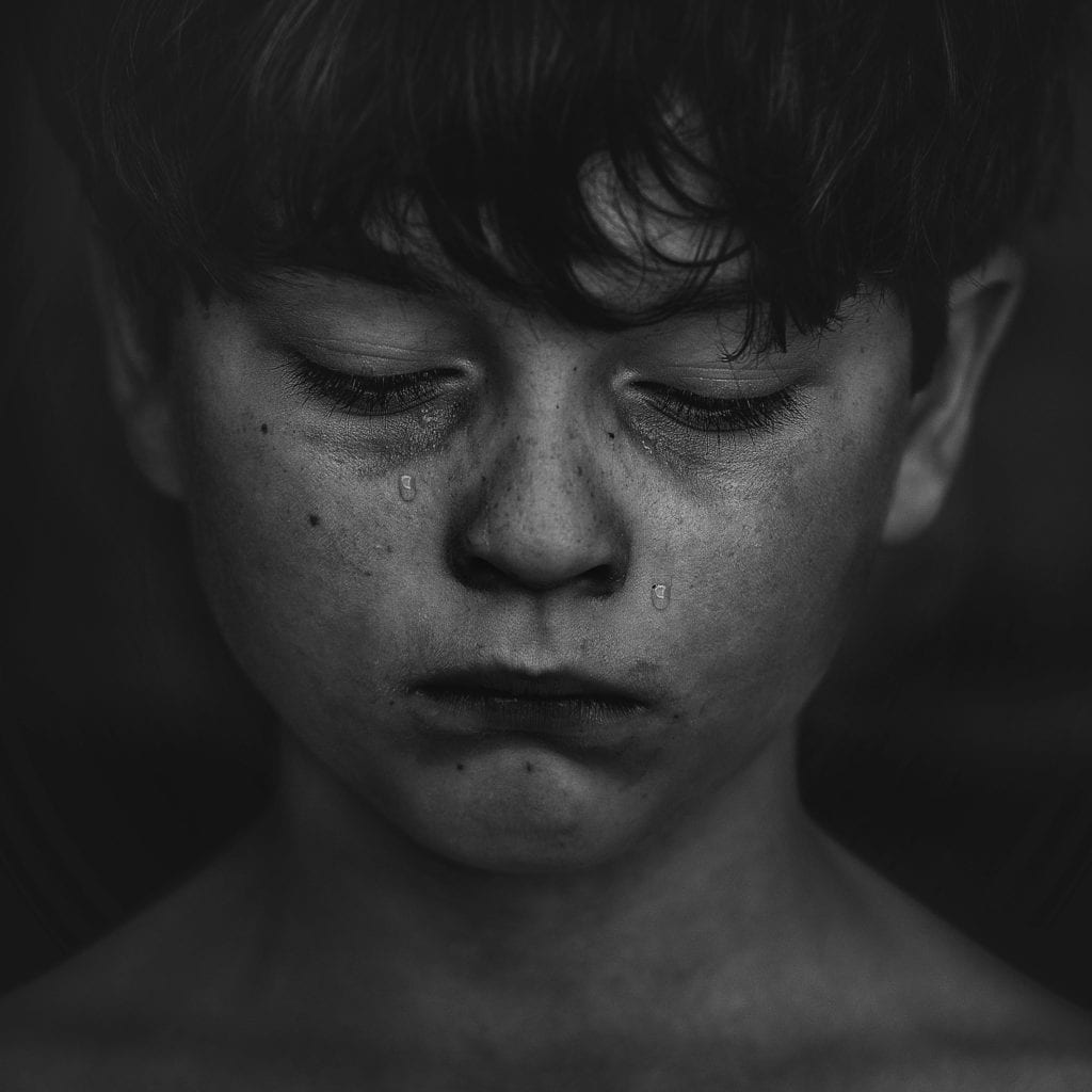 black and white photo of a boy with dark hair crying
