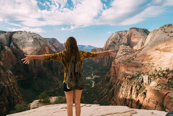 woman-standing-on-overlook-with-arms-spread-while-looking-at-view-of-valley