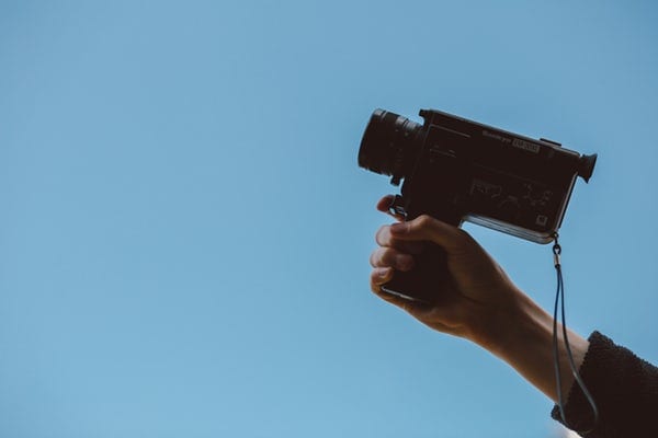 hand-holding-camcorder-against-light-blue-background