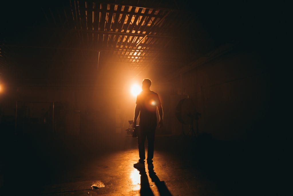 man with camera backlit showing how video storytelling can create an emotional response, such as fear. 