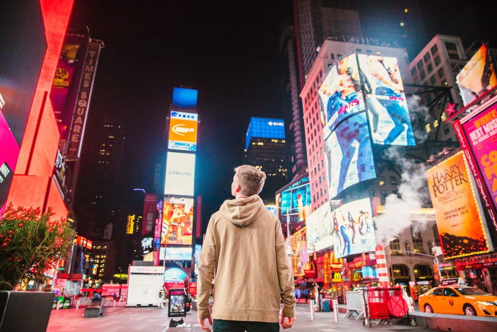 Young man looks up at Times Square signage