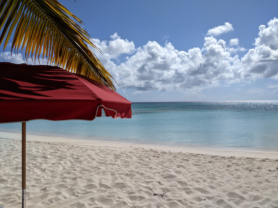 a beach umbrella in the foreground with the calm ocean beyond